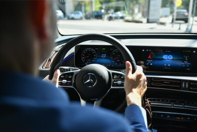 Jemand sitzt am Steuer eines Mercedes.
