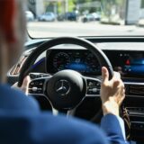Jemand sitzt am Steuer eines Mercedes.