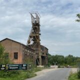 Das Foto zeigt ein altes Industriegebäude mit einem Förderturm davor.