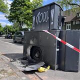 Mit Farbe besprühter Panzerblitzer an Langenbochumer Straße, davor sind Reste der verbrannten Mülltonne zu sehen. Absperrband flattert.