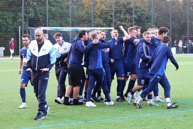 Die Mannschaft von SuS Polsum feiert, Trainer Emanuel Kastrinos (vorn links) bewahrt einen klaren Kopf. So soll das auch in Zukunft beim Dorfklub laufen.