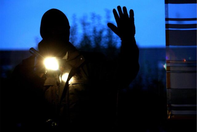 Umriss eines Mannes mit Maske und Taschenlampe in der Hand
