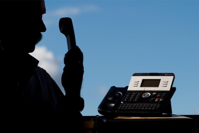 Ein Mann hält einen Telefonhörer in der Hand.