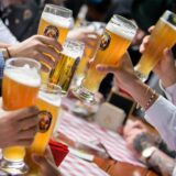 Menschen stoßen mit Weizengläsern in einem Biergarten an.