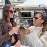Zwei Frauen stoßen mit einem Glas Wein an.