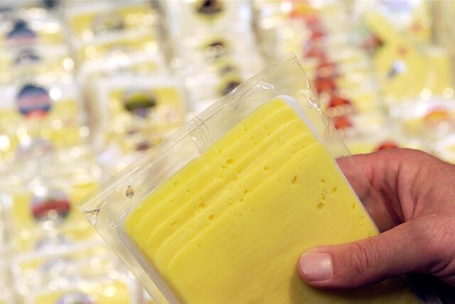 Ein Mann hält in einem Supermarkt eine Packung Käse in der Hand.