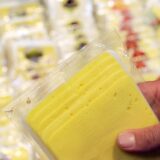 Ein Mann hält in einem Supermarkt eine Packung Käse in der Hand.