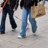 Zwei junge Frauen gehen am verkaufsoffenen Sonntag mit Einkaufstaschen und ihren Hunden durch die Fußgängerzone.