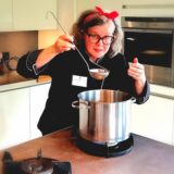 Elke Schumacher steht mit einem großen Schöpflöffel an einem Suppentopf.