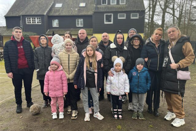Ein Teil der 27 Geflüchteten steht zusammen mit Vermieterin Iris Räther und einer Dolmetscherin auf dem Geländer der Herberge der Herrlichkeit in Dorsten.
