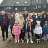 Ein Teil der 27 Geflüchteten steht zusammen mit Vermieterin Iris Räther und einer Dolmetscherin auf dem Geländer der Herberge der Herrlichkeit in Dorsten.