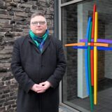Claus Althoff, der Pfarreiratsvorsitzender der Pfarrei Heilige Edith Stein, steht vor dem Eingang der Pfarrei.