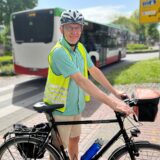 Ein Mann mit Warnweste und Fahrradhelm lächelt in die Kamera.