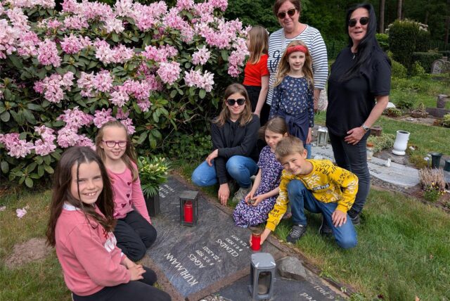 Neun Schüler der OGS-Hullern stehen gemeinsam mit OGS-Leiterin Meike Rabenschlag und pädagogischen Fachkraft Marie Backhaus an einem Grab. Sam legt eine Gedenkkerze nieder.