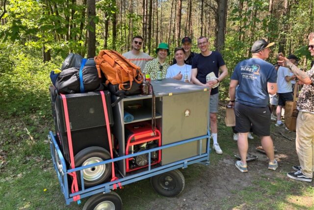 Ein Maiwagen mit einer Gruppe Menschen dahinter. Der Maiwagen hat Musikboxen mit an Board.