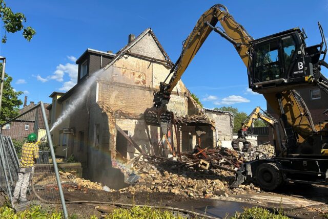 Ein Bagger reißt die letzten Reste der Wände des Hauses ein.