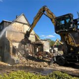 Ein Bagger reißt die letzten Reste der Wände des Hauses ein.