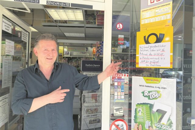 Kiosk-Inhaber Andreas Wendt weist auf ein Hinweisschild an der Tür.