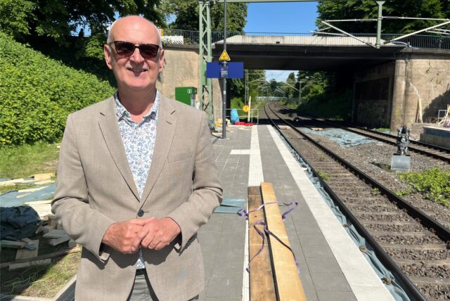 Carsten Löcker steht mit Sonnenbrille am Bahnsteig.