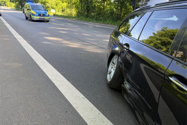 Beschädigtes Auto und Streifenwagen auf einer Straße
