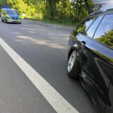 Beschädigtes Auto und Streifenwagen auf einer Straße