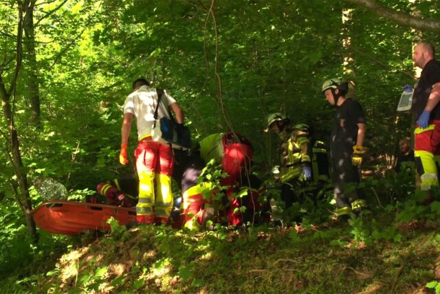 Rettungskräfte der Feuerwehr und Höhenretter kümmern sich um einen verletzten Jugendlichen, der auf einer roten Trage liegt.