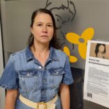 Eine Frau steht neben einem Plakat, auf dem „Rettet die Beleghebammen“ steht.