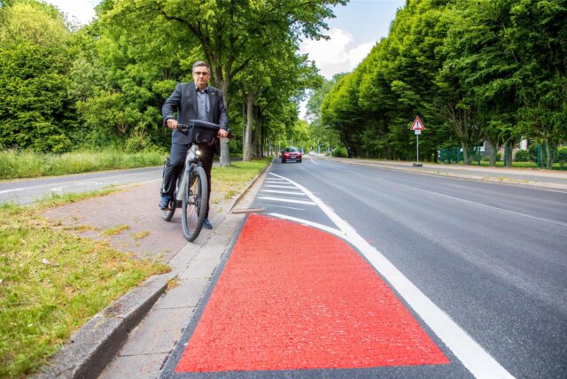 Patrick Berner (ADFC) steht in Herten mit seinem Fahrrad an der Straße Über den Knöchel. Der Radweg führt an dieser Stelle vom Gehweg auf die Straße.