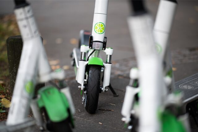 E-Scooter mit dem Logo des Anbieters „Lime“ stehen auf einem Gehweg.