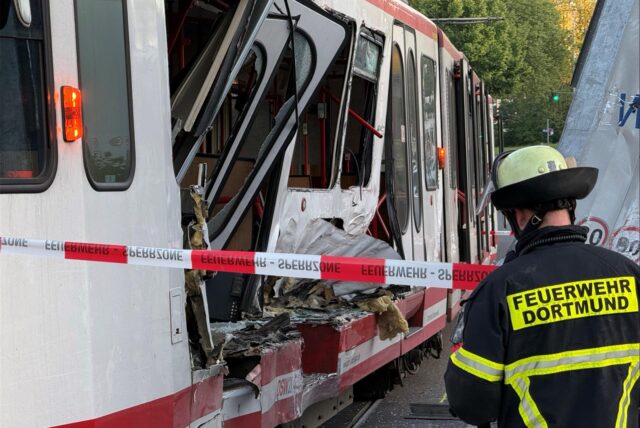 Ein Feuerwehrmann steht vor der völlig zerstörten Straßenbahn in Dortmund.