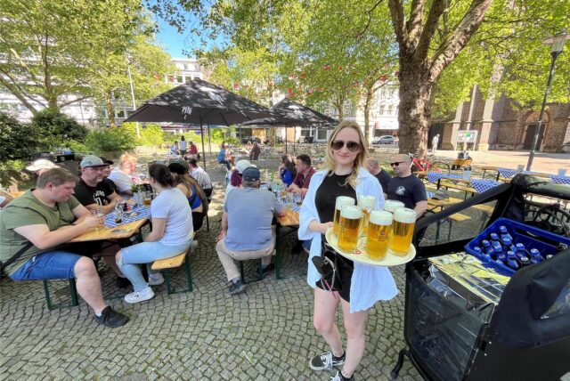 Lea bedient mit einem gut gefüllten Tablett Gäste auf dem Antoniusplatz in Herten-Mitte.