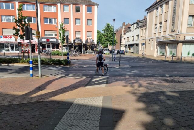 Ein Radfahrer schiebt sein Rad über einen Zebrastreifen.