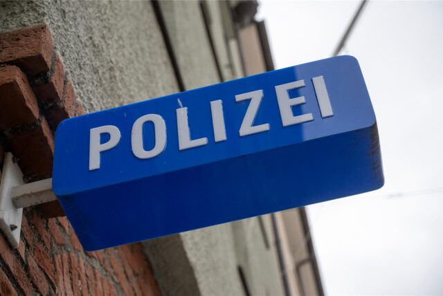 An einer Hauswand hängt ein Schild „Polizei“.