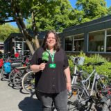MZ-Volontärin Laura Wunderlich berichtet live vom Pedelec-Training für Senioren in Marl und steht vor dem Start der Übertragung mit dem Mikro in der Hand vor dem Fahrradständer mit Fahrrädern an der insel-VHS in Marl.