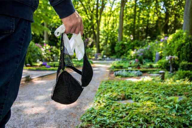 Auf dem Waldfriedhof in Herten ist eine Männerhand zu sehen, die Damen-Unterwäsche hält. (Nachgestellte Szene)