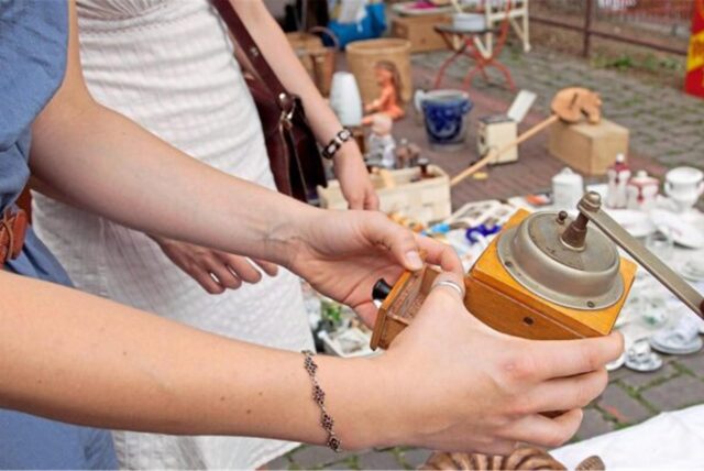 Frauen begutachten eine alte Kaffeemühle. Zu sehen sind nur die Hände.
