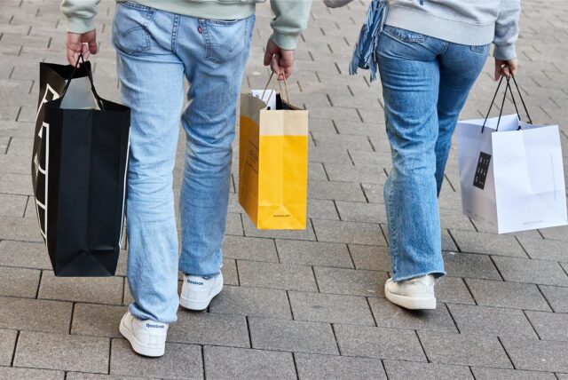 Eine Frau und ein Mann tragen am verkaufsoffenen Sonntag mehrere Einkaufstüten.