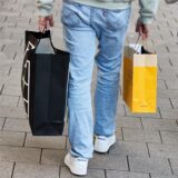 Eine Frau und ein Mann tragen am verkaufsoffenen Sonntag mehrere Einkaufstüten.