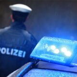 Ein Polizist hinter einem Polizeiwagen.
