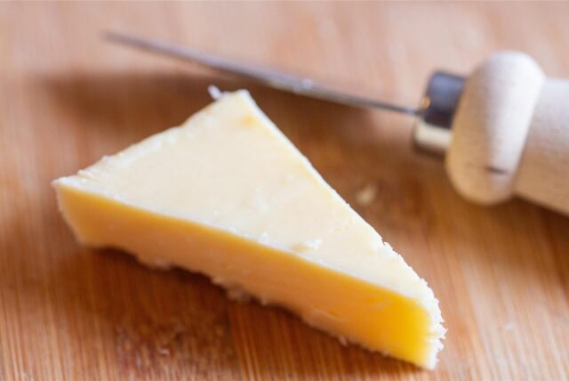 Ein Stück Käse liegt auf einem Brett.