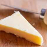 Ein Stück Käse liegt auf einem Brett.
