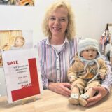 Christiane Karls mit Puppe kündigt den Räumungsverkauf an.