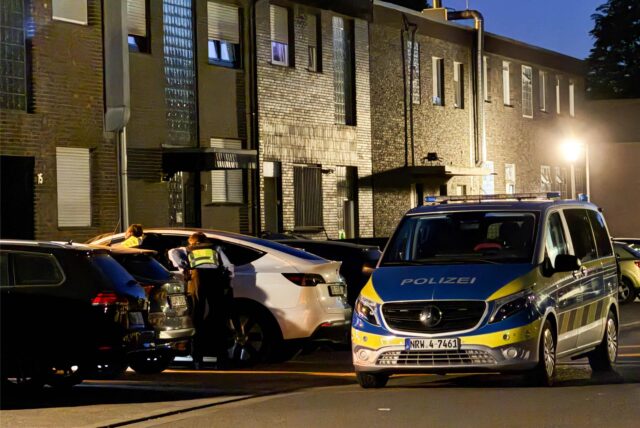 Ein Polizeiwagen steht vor einer Häuserreihe mit geparkten Fahrzeugen in Gladbeck.