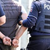 Polizeibeamte führen eine Person in Handschellen ab.