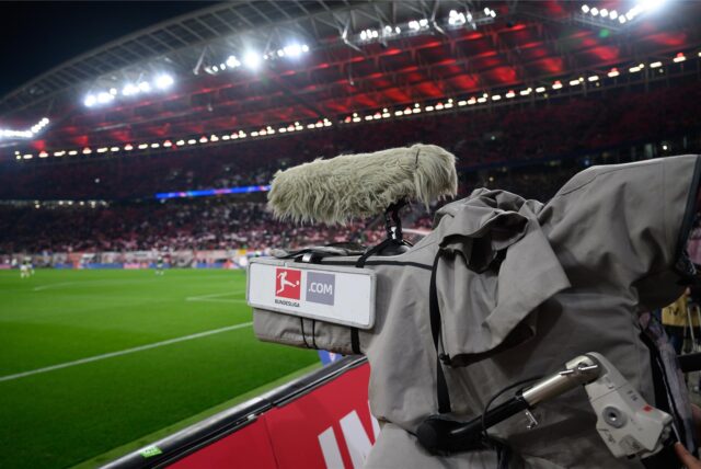 Eine TV-Kamera steht in einem Fußballstadion am Spielfeldrand.