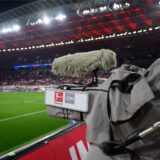 Eine TV-Kamera steht in einem Fußballstadion am Spielfeldrand.