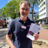 Stefan Arhelger vom Deutschen Roten Kreuz hält Informationsbroschüren zum Thema Schuldnerberatung in die Kamera.