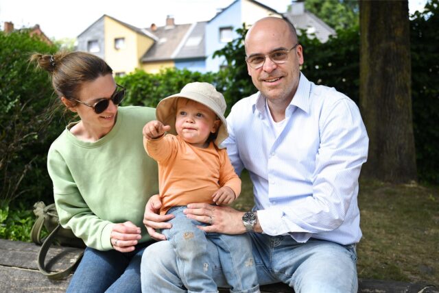 Kita-Eltern aus Recklinghausen-Süd mit ihrem Kleinkind in der Mitte auf dem Schoß.