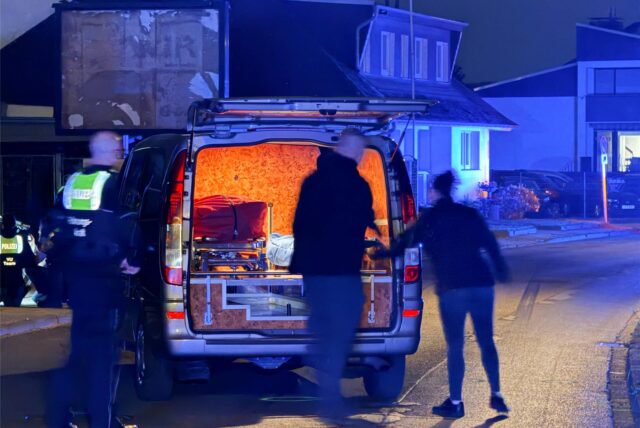 Die Klappe eines Krankenwagens ist geöffnet, eine Bahre steht darin. Menschen sind vor dem Auto.
