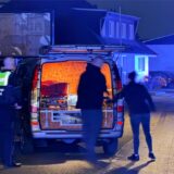 Die Klappe eines Krankenwagens ist geöffnet, eine Bahre steht darin. Menschen sind vor dem Auto.